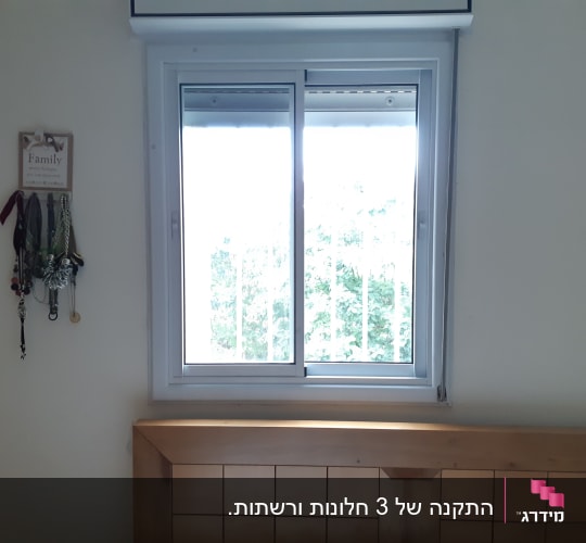 חלון אלומיניום עם מסגרת לבנה וקירבה למיטה
